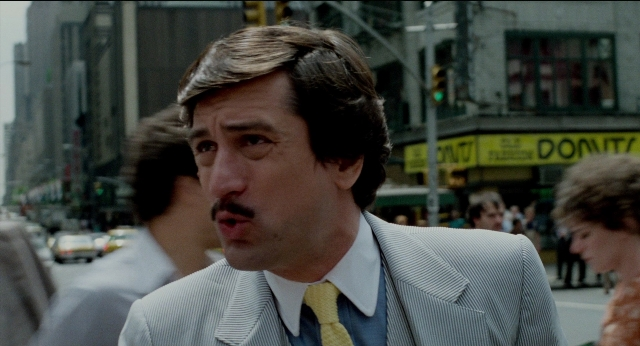 Wide shot frame from The King of Comedy — walking, street, suit