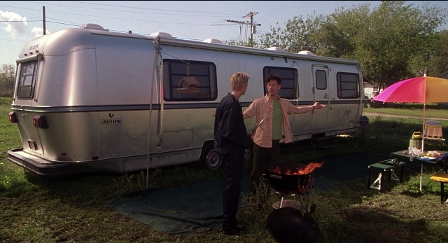 Wide shot frame from The New Guy — standing, table, umbrella