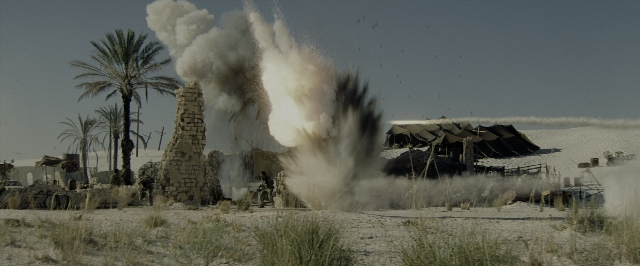 Wide shot frame from Transformers — smoke, person, palm tree