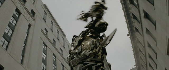 Wide shot frame from Transformers — standing, hat, hand