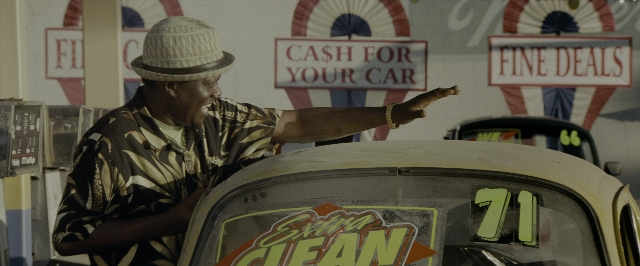 Wide shot frame from Transformers — standing, hat, car