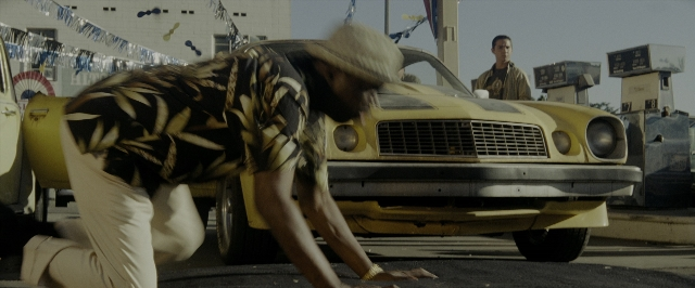 Wide shot frame from Transformers — standing, hat, car