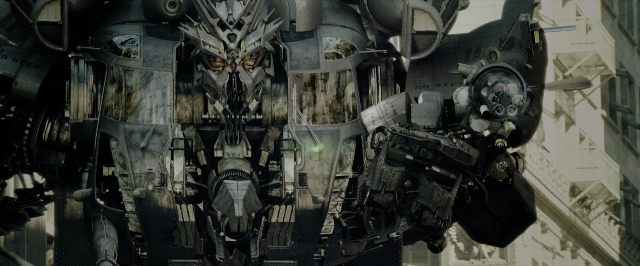 Wide shot frame from Transformers — hat, face, building