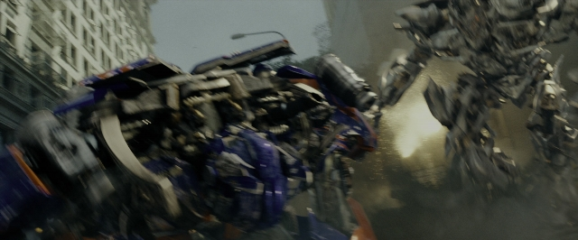 Wide shot frame from Transformers — suit, gun, smoke