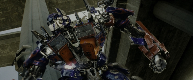 Wide shot frame from Transformers — standing, hat, hand