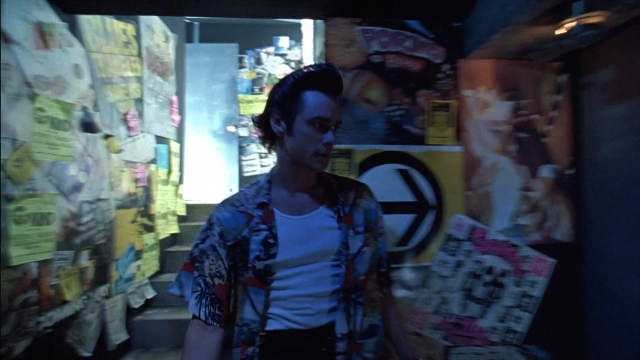 Wide shot frame from Ace Ventura: Pet Detective — standing, room, shirt