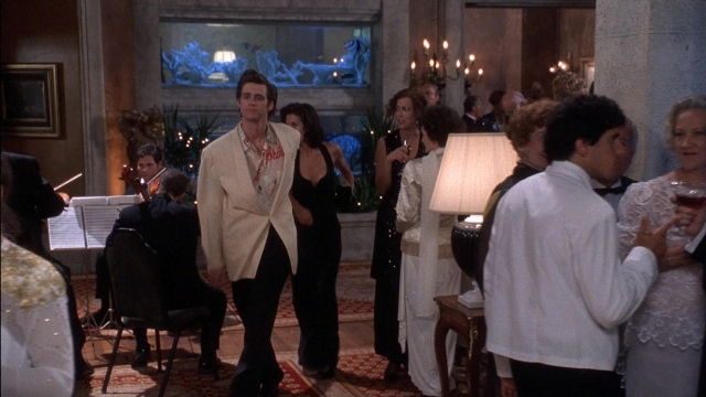 Wide shot frame from Ace Ventura: Pet Detective — sitting, standing, room