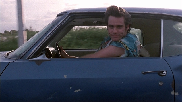 Wide shot frame from Ace Ventura: Pet Detective — sitting, door, street