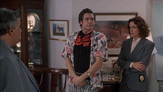 Wide shot frame from Ace Ventura: Pet Detective — standing, room, suit