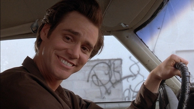 Wide shot frame from Ace Ventura: Pet Detective — sitting, shirt, hair