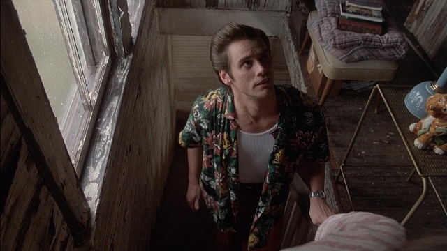 Wide shot frame from Ace Ventura: Pet Detective — standing, room, table