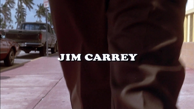 Wide shot frame from Ace Ventura: Pet Detective — walking, street, car