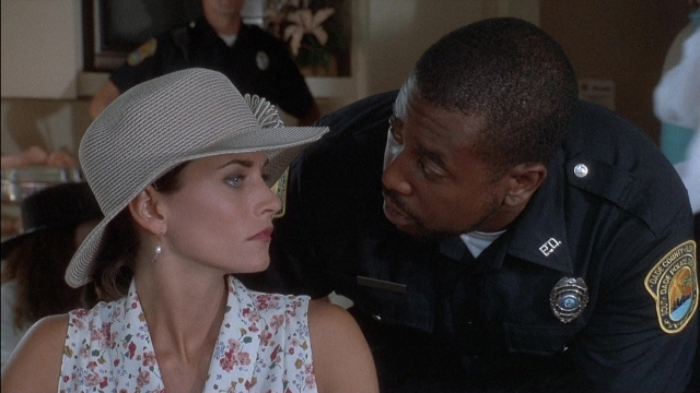 Wide shot frame from Ace Ventura: Pet Detective — table, dialogue, hat