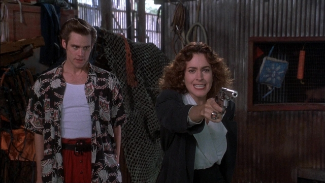 Wide shot frame from Ace Ventura: Pet Detective — standing, room, hand