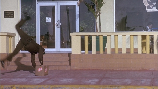 Wide shot frame from Ace Ventura: Pet Detective — sitting, door, street