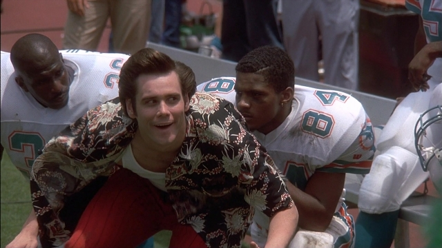 Wide shot frame from Ace Ventura: Pet Detective — sitting, shirt, face
