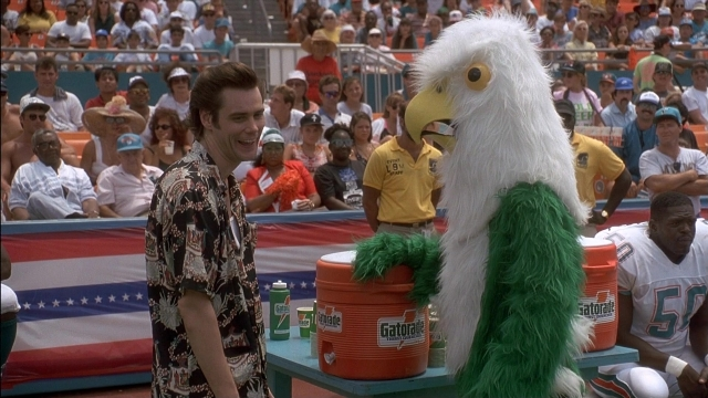 Wide shot frame from Ace Ventura: Pet Detective — standing, table, shirt