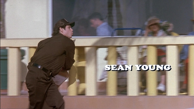Wide shot frame from Ace Ventura: Pet Detective — sitting, standing, hat