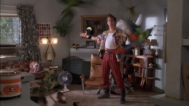 Wide shot frame from Ace Ventura: Pet Detective — standing, room, table