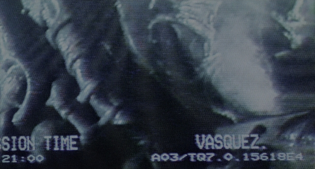 Wide shot frame from Aliens — hat, face, poster