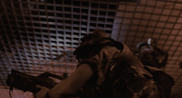 Wide shot frame from Aliens — room, hat, gun