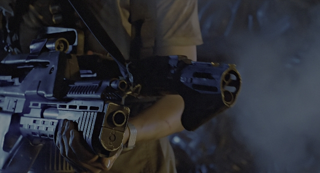 Wide shot frame from Aliens — uniform, hand, gun