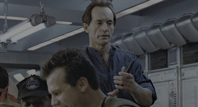 Wide shot frame from Aliens — standing, room, hat