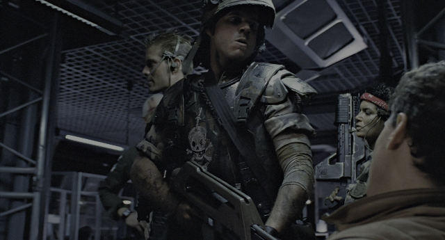 Wide shot frame from Aliens — dialogue, hat, gun