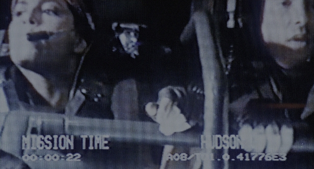 Wide shot frame from Aliens — sitting, street, hat