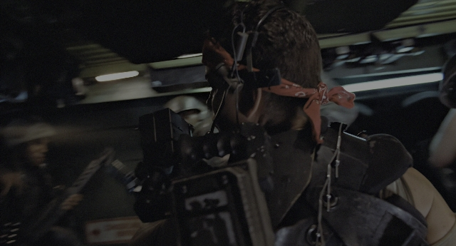 Wide shot frame from Aliens — sitting, room, hand