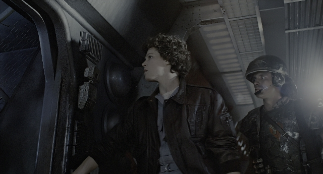Wide shot frame from Aliens — standing, room, hat