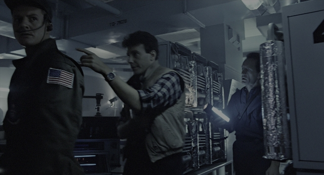 Wide shot frame from Aliens — standing, room, hat