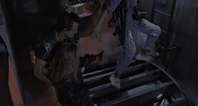 Wide shot frame from Aliens — standing, suit, gun
