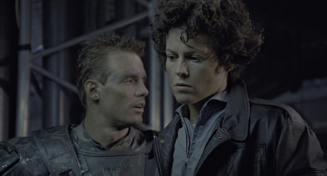 Medium shot frame from Aliens — standing, jacket, face