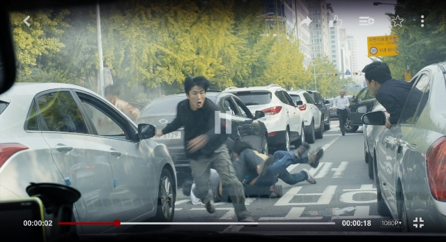 Wide shot frame from Busanhaeng — street, car, hand