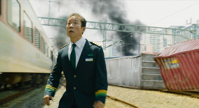 Wide shot frame from Busanhaeng — standing, uniform, suit