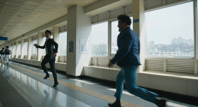 Medium shot frame from Busanhaeng — walking, suit, person