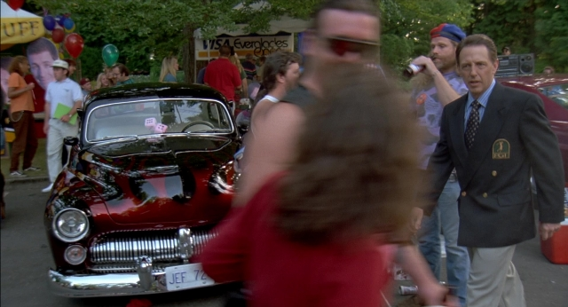 Wide shot frame from Happy Gilmore — plate, street, car