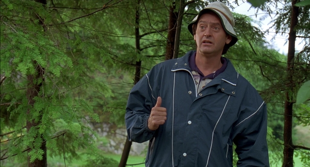 Wide shot frame from Happy Gilmore — standing, hat, hand