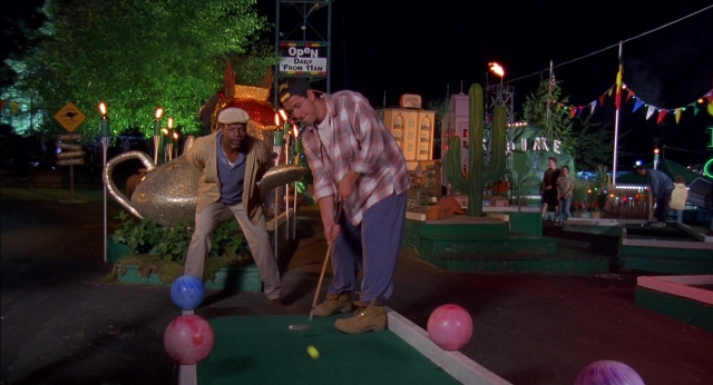 Wide shot frame from Happy Gilmore — standing, hat, hand