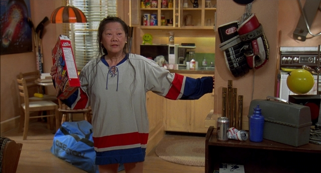 Wide shot frame from Happy Gilmore — standing, kitchen, hand
