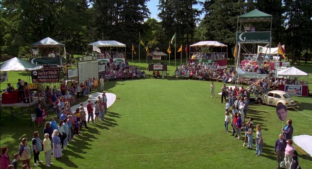 Wide shot frame from Happy Gilmore — flag, car, person