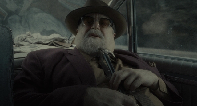 Medium shot frame from Inside Llewyn Davis — sitting, hat, car
