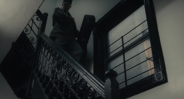 Wide shot frame from Inside Llewyn Davis — walking, hat, hand