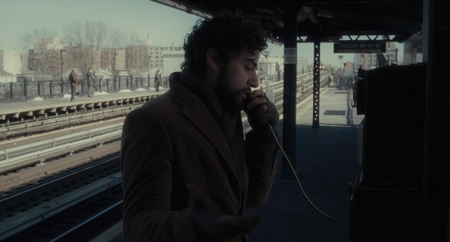 Wide shot frame from Inside Llewyn Davis — standing, phone, coat