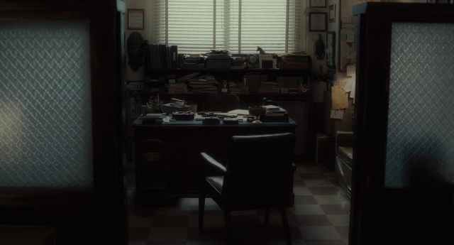 Wide shot frame from Inside Llewyn Davis — desk, room, door