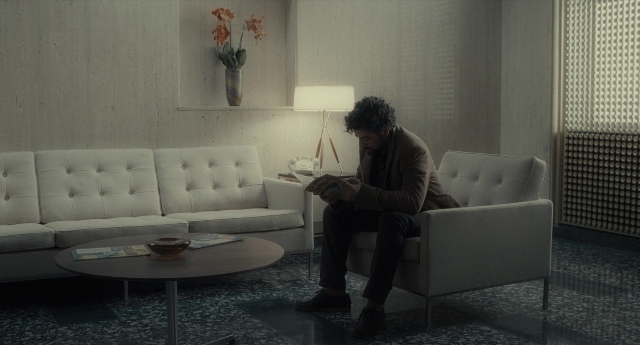Wide shot frame from Inside Llewyn Davis — sitting, book, room
