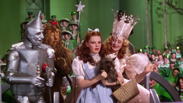 Wide shot frame from The Wizard of Oz — standing, hat, dog