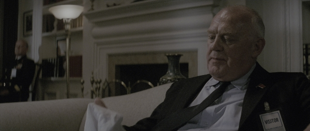Wide shot frame from The Hunt for Red October — sitting, room, suit