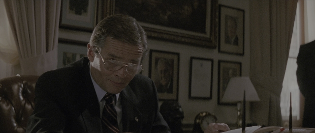 Wide shot frame from The Hunt for Red October — sitting, room, suit